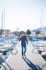 Giovane uomo che parla su smartphone mentre cammina sul molo del lago — Foto stock