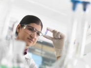 Female scientist viewing sample in eppendorf ahead of DNA testing in a laboratory. — Stock Photo