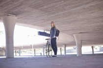 Young woman waiting with bicycle in city underpass — Stock Photo