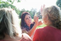 Feminino adultos amigos aplicando maquiagem no pôr do sol parque festa — Fotografia de Stock
