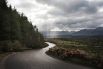 Camino sinuoso a través de las montañas, Escocia, Reino Unido - foto de stock