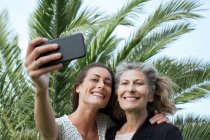 Mujer mayor y su hija tomando selfie smartphone - foto de stock