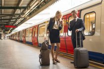 Homme d'affaires et femme d'affaires textos sur plate-forme, station de métro, Londres, Royaume-Uni — Photo de stock