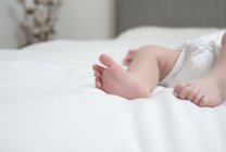 Ноги маленькой девочки лежат на кровати — стоковое фото