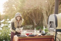 Reifes Hippie-Weibchen bereitet Essen auf Gartentisch zu — Stockfoto