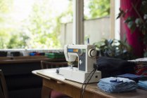Máquina de coser en la mesa con tela y tijeras - foto de stock