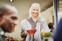 Seniorin trägt Schalen mit Salat nach draußen — Stockfoto