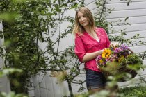 Молода жінка з кошиком квітів в саду — стокове фото