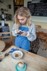 Jovem mulher no café, usando smartphone — Fotografia de Stock