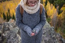 Mujer joven de pie en la montaña, sosteniendo la roca en la mano enguantada, Óblast de Sverdlovsk, Rusia - foto de stock