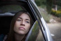 Jovem mulher olhando através da janela dentro do carro — Fotografia de Stock