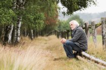 Uomo anziano seduto sul tronco — Foto stock
