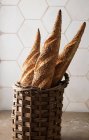 Basket of baguettes on rustic kitchen table — Stock Photo