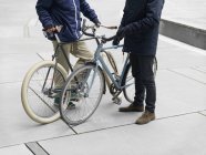 Neck down view of urban cyclists standing beside bicycle — Stock Photo