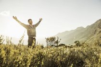 Man in field, arms raised smiling — Stock Photo