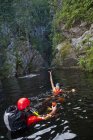 Uomo e donna in casco che festeggiano nuotando in acqua nel canyon — Foto stock
