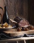 Whole roast beef and baked potatoes on table — Stock Photo