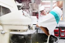 Пекарь наливает муку в смеситель — стоковое фото