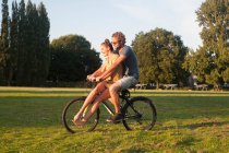 Romântico jovem casal de bicicleta juntos no parque — Fotografia de Stock