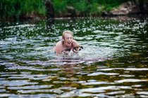Joven y su perro jugando en el río - foto de stock