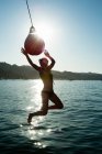 Young woman swinging from boat fender, Sausalito, California, USA — Stock Photo