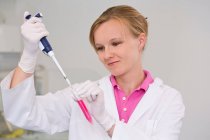 Female scientist pipetting liquid for reaction mixture — Stock Photo
