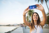 Young woman taking smartphone selfie on waterfront, Manila, Philippines — Stock Photo