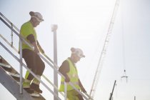 Engineers walking on steps in sunlight working at wind farm construction site — Stock Photo