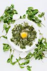 Plate of raw egg with herbs — Stock Photo