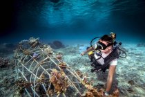 Unterwasseraufnahme eines Tauchers, der eine Sekrete auf dem Meeresboden fixiert (künstliches Stahlriff mit elektrischem Strom), Lombok, Indonesien — Stockfoto