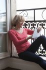 Женщина с цифровым планшетом на балконе — стоковое фото