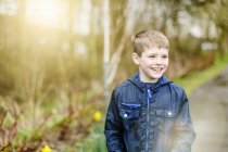 Хлопчик стоїть на відкритому повітрі в лісі в м'якому світлі — стокове фото
