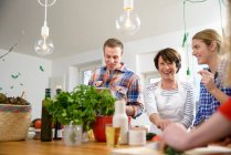 Mother with grown up children preparing food in kitchen — Stock Photo