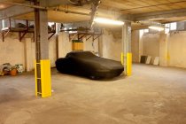 Автомобіль в чорній обкладинці припаркований в гаражі — стокове фото