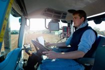 Jeune homme conduisant tracteur utilisant le système de positionnement mondial — Photo de stock