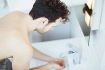 Giovane uomo lavarsi le mani nel lavandino del bagno — Foto stock