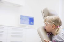 Menina sentada para trás na cadeira do dentista olhando para longe — Fotografia de Stock