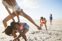Young man and three female friends playing leapfrog on beach, Cape Town, South Africa — Stock Photo