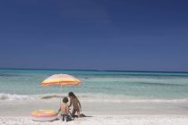 Girl and brother playing under beach umbrella on beach, Majorca, Spain — Stock Photo
