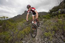 Joven ciclismo de montaña por sendero de montaña - foto de stock