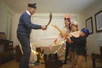 Senior man in pirate hat having sword fight with dressed up grandchildren — Stock Photo