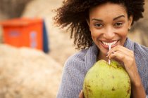 Retrato de una joven bebiendo leche de coco en la playa de Ipanema, Rio De Janeiro, Brasil - foto de stock