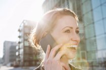 Взрослая женщина, использующая мобильный телефон при солнечном свете на открытом воздухе — стоковое фото