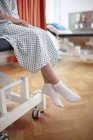 Girl sitting on hospital bed, wearing examination gown — Stock Photo