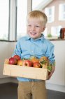 Портрет хлопчика, що тримає ящик з яблуками — стокове фото