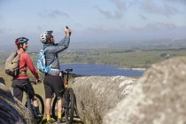 Велогонщики с велосипедами на скалистом обнажении фотографируют — стоковое фото