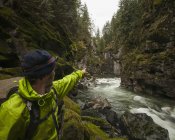 Escursionista con faro rivolto verso le scogliere di granito di 300 piedi che racchiudono il Parco provinciale del Canyon di Coquihalla e i Tunnel dell'Otello. Parte del Trans-Canada Trail, Hope, British Columbia, Canada — Foto stock