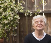 Porträt einer lächelnden Seniorin im Garten, die nach oben blickt — Stockfoto