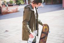 Молодий чоловік міський скейтбордист тримає пляшку води — стокове фото