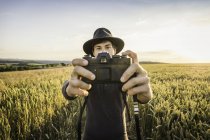Человек делает селфи с камерой SLR в поле — стоковое фото